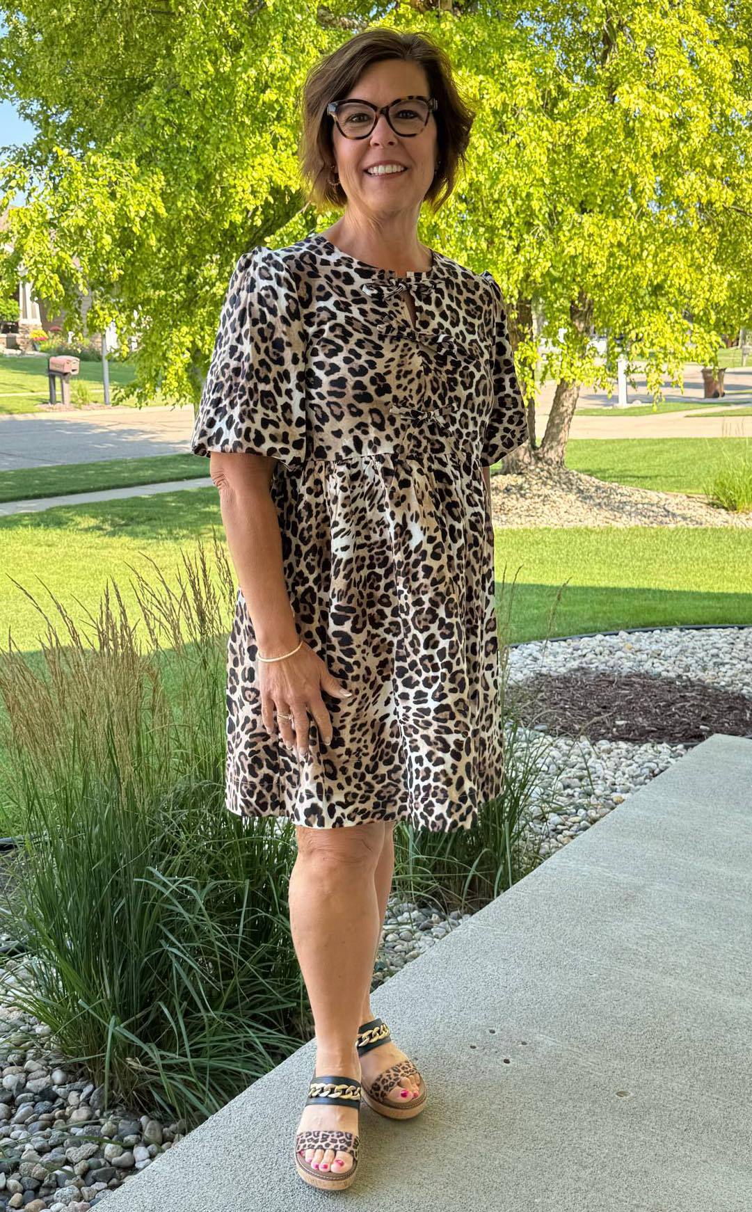 Royanna Stratmoen standing outside in a leopard print dress and coordinating sandals, smiling confidently as she models bold style for women 40+.