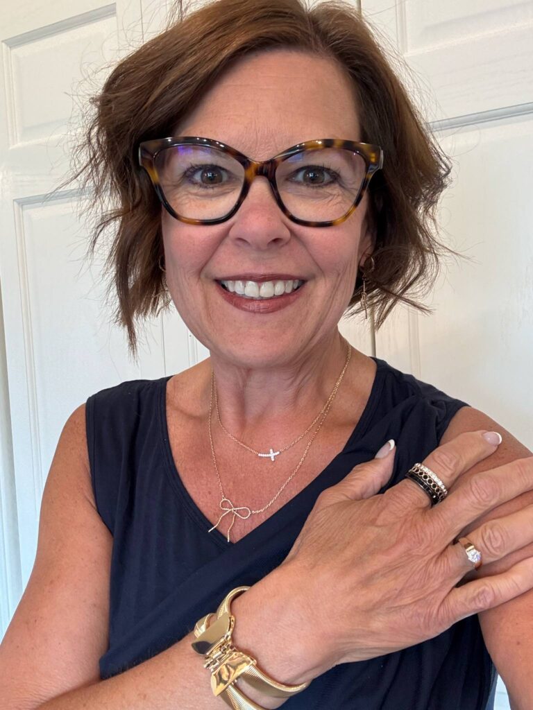 Royanna Stratmoen, Color and Style Coach for Women 40+, smiling and accessorized with gold jewelry, layered necklaces, and statement glasses.